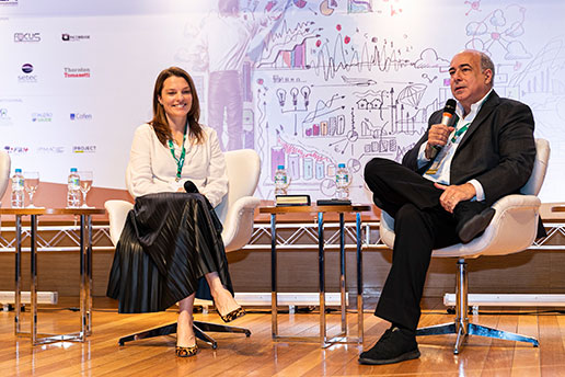 Registro de dois convidados, sentados e enquanto falam, durante o Simpósio Internacional.