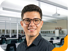 Estudante universitário sorrindo, usando camiseta verde, no laboratório da Unidade de Ensino Einstein.